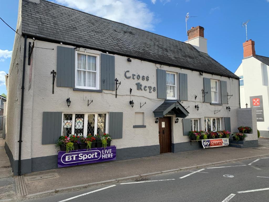 un bâtiment blanc avec un panneau indiquant la compassion des clients dans l'établissement The Crosskeys Inn, à Usk