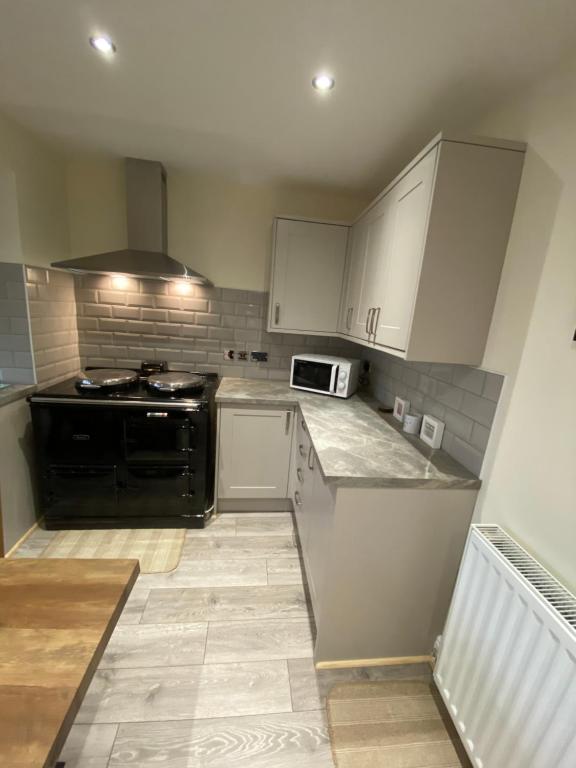 a kitchen with white cabinets and a black stove at Prince Cottage in West Auckland