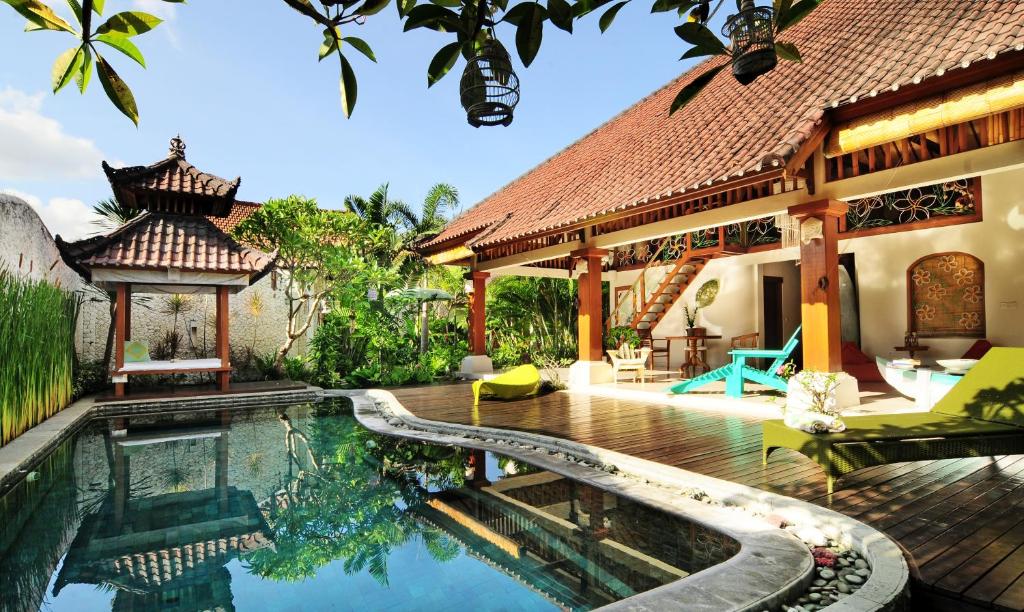 a swimming pool in front of a house at Villa Domus De Janas in Seminyak