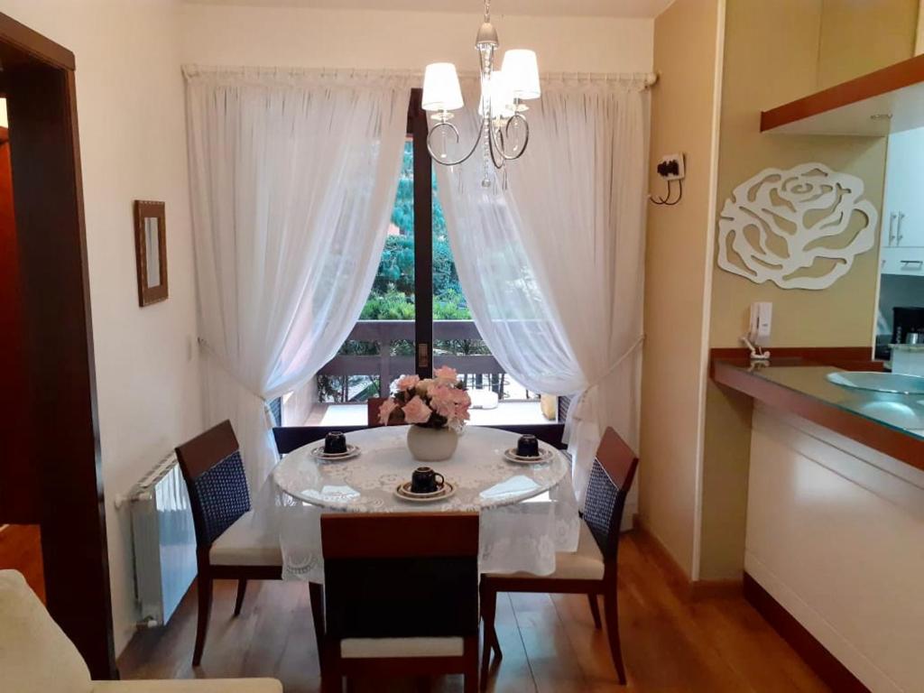 a dining room with a table and a window at Resort com Natureza no Centro in Gramado