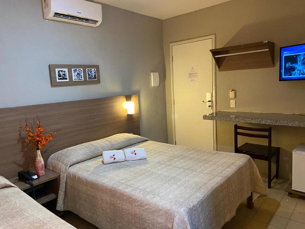 a hotel room with two beds and a tv at Hotel Saveiro in Recife