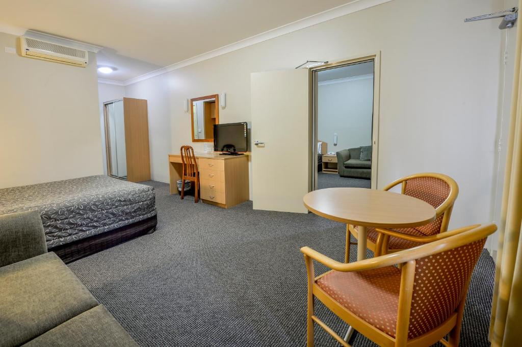 a hotel room with a bed and a table and chairs at Golden Guitar Motor Inn in Tamworth