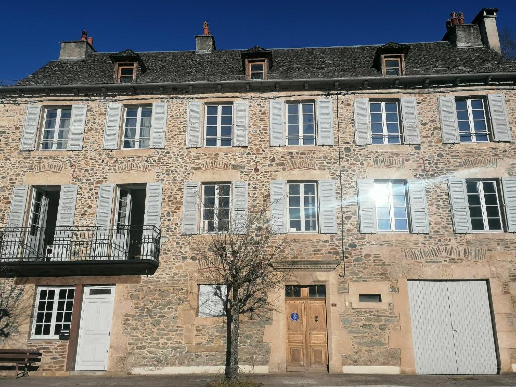 un gran edificio de ladrillo con puertas y ventanas blancas en Gîte Les Pieds dans l'Olt - Ultreïa, en Estaing