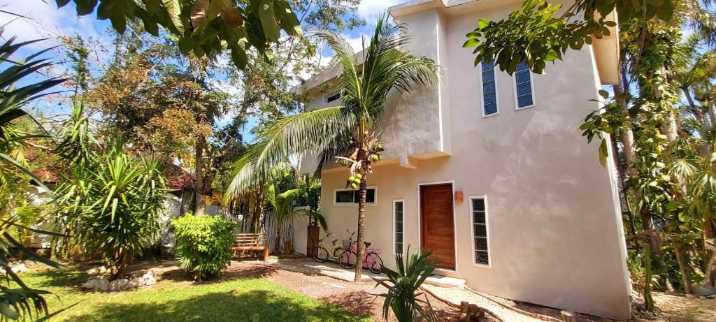 a white house with a garden and trees at MINI PINI BIRD WATCHING AND CENOTE Loft in Cozumel