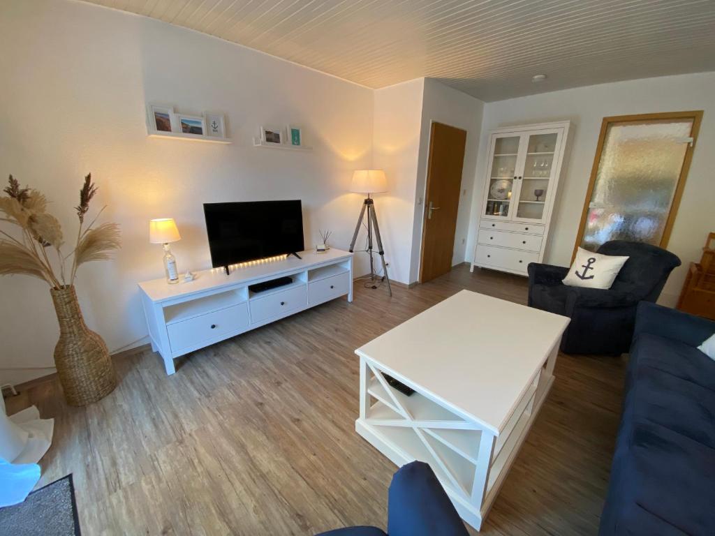 ein Wohnzimmer mit einem blauen Sofa und einem TV in der Unterkunft Birkenweg Ankerplatz I in Carolinensiel