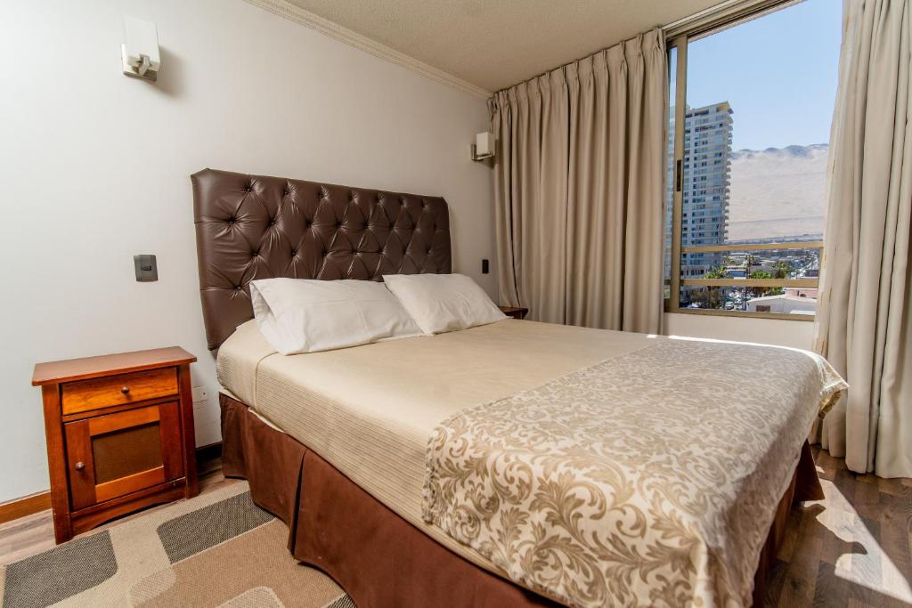 a bedroom with a large bed with a large window at Departamentos Alpro Cavancha in Iquique