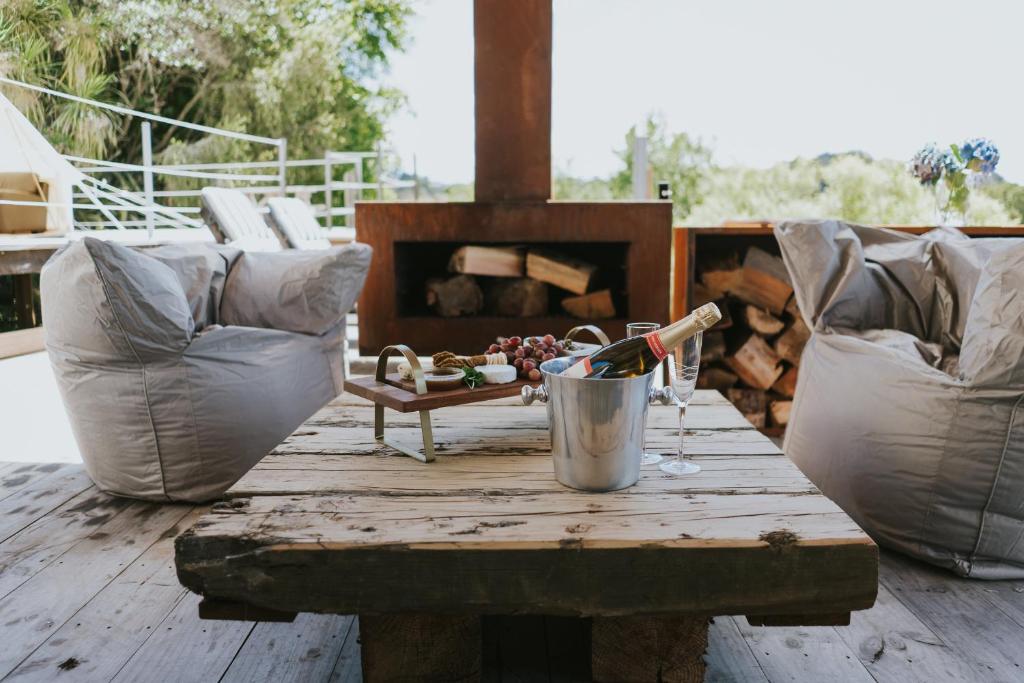 羅托魯阿的住宿－Oakridge Glamping，庭院里的木桌和一瓶葡萄酒