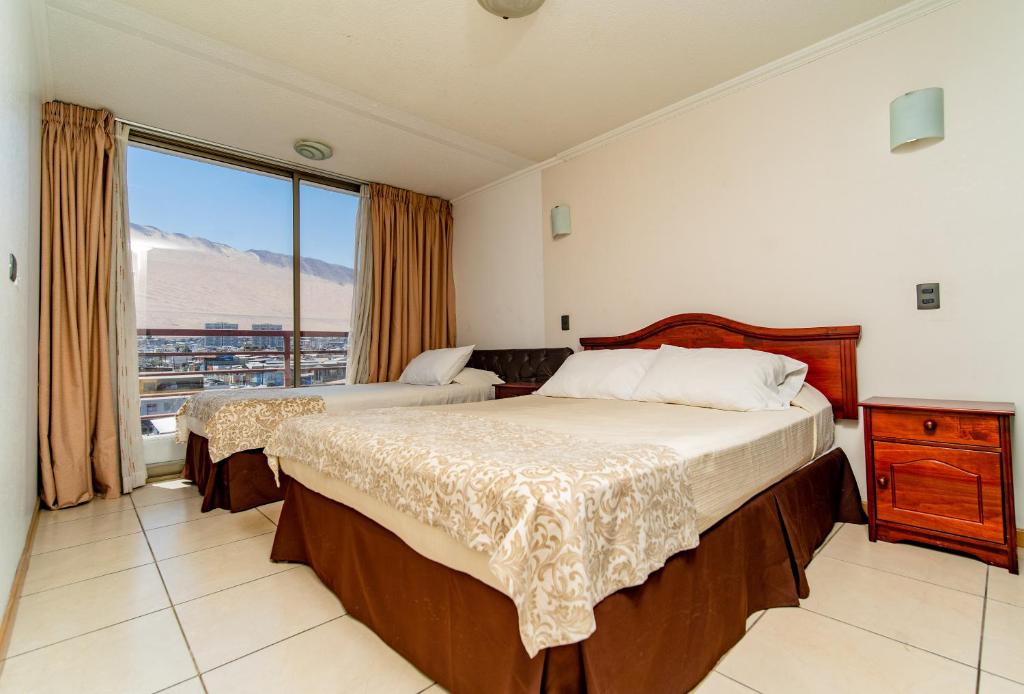 sypialnia z 2 łóżkami i dużym oknem w obiekcie Alpro Urbano Oriente w mieście Iquique