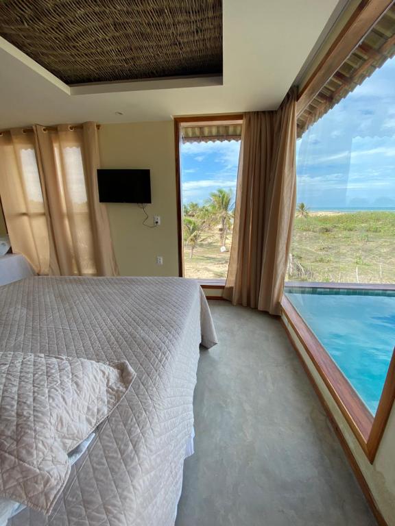 a bedroom with a bed and a view of the ocean at Vila do Alto - Beach Homes in Itarema