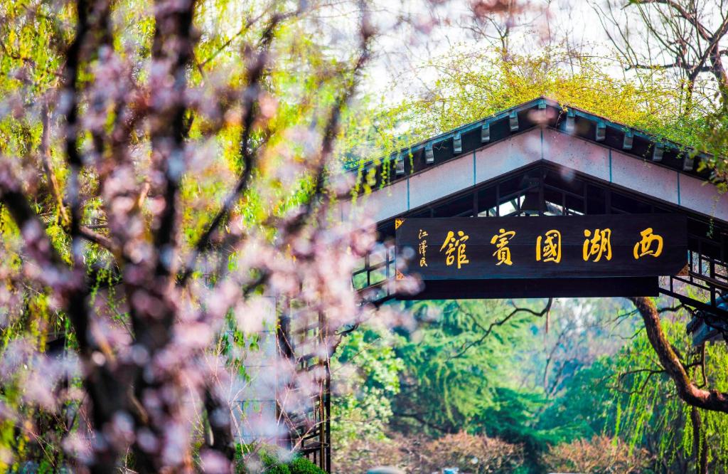 un puente con escritura asiática en un bosque en West Lake State Guest House, en Hangzhou