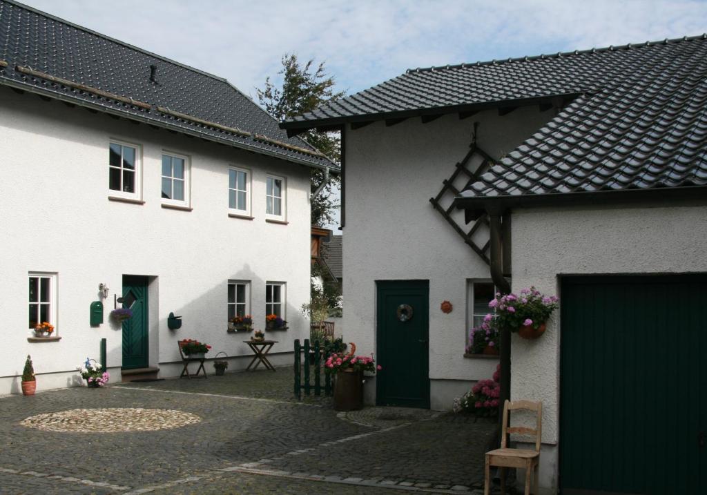zwei weiße Häuser mit grünen Türen und einem Innenhof in der Unterkunft Ferienhaus Ginsterblüte in Schleiden