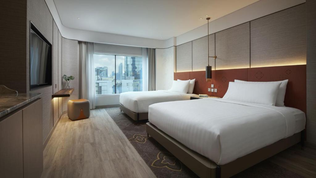 a hotel room with two beds and a television at Amari Bangkok in Bangkok