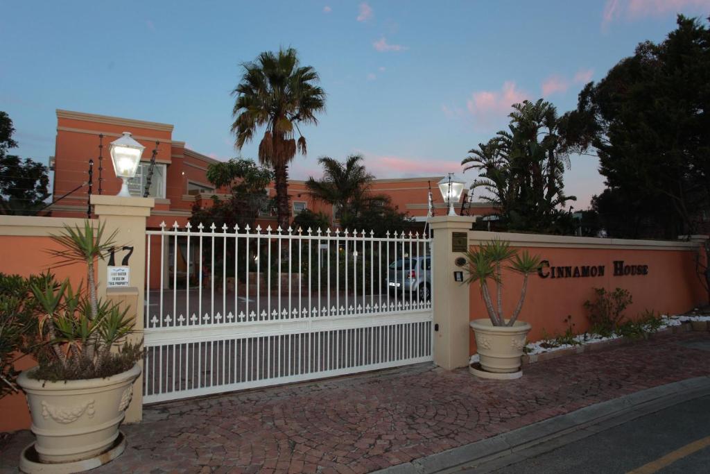 una valla blanca frente a un edificio con palmeras en Cinnamon House Bed & Breakfast, en Ciudad del Cabo