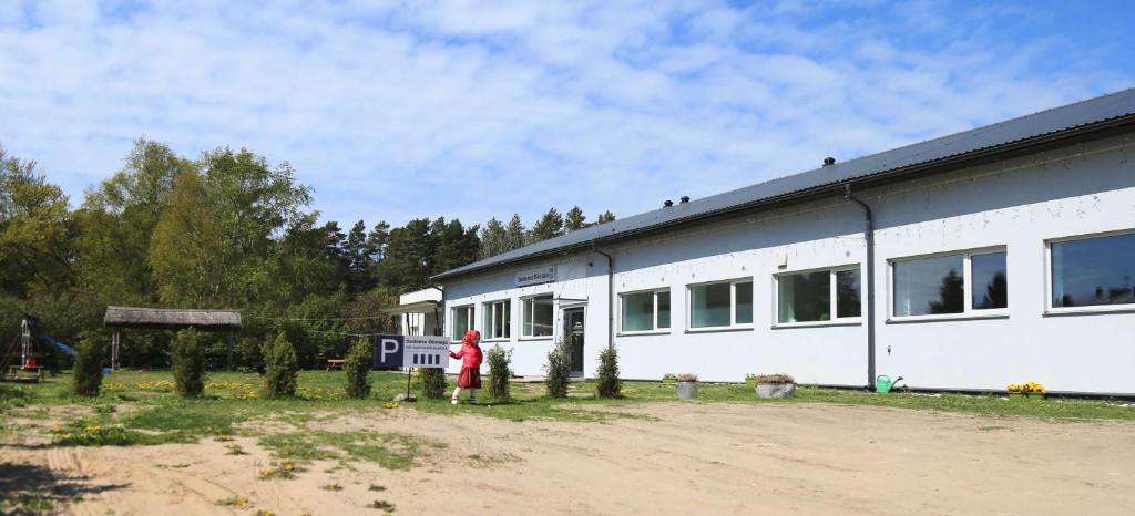 a white building with a person standing in front of it at Kihnu Sadama Öömaja in Lemsi