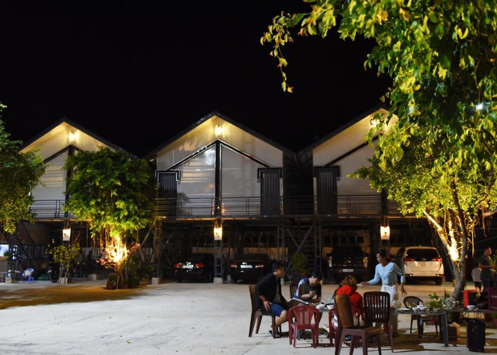 un grupo de personas sentadas en mesas frente a un edificio en Mobile Home Ho Tram Pristine Beach, en Thuận Biên