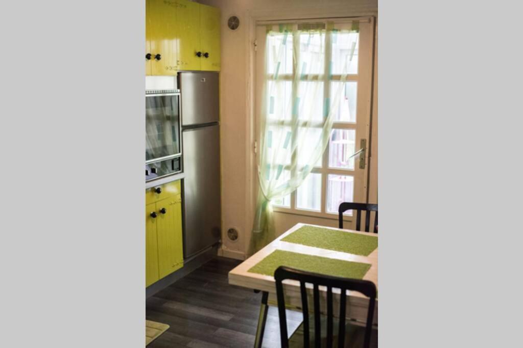 a kitchen with yellow cabinets and a table with chairs at Entre parc et Haras in Hennebont