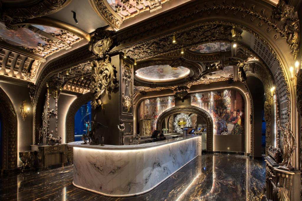 A lavish dark lobby or reception space with a marble desk and elaborate gold-and-black ornament.