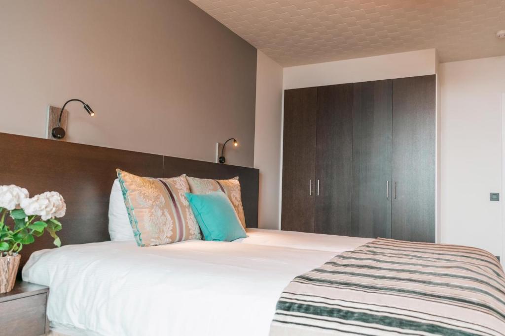 een slaapkamer met een groot bed met een houten hoofdeinde bij The Memlinc in Knokke-Heist