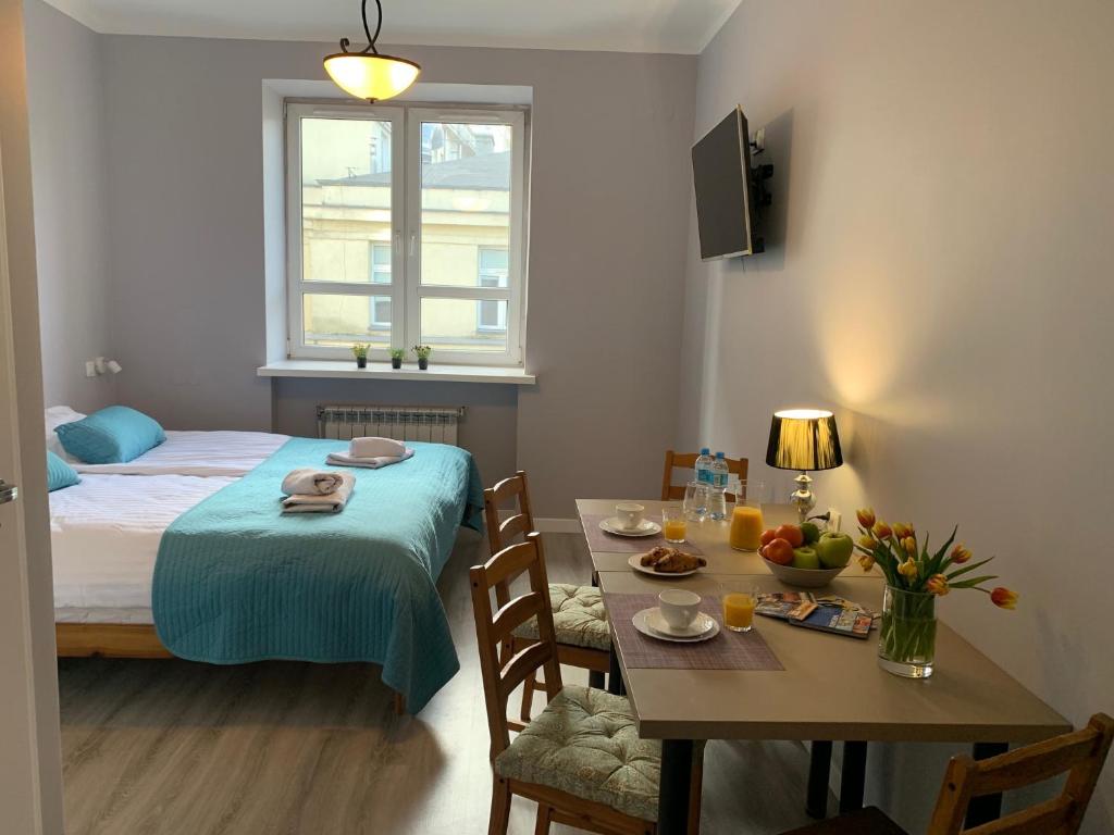 ワルシャワにあるJasna Hotelikのテーブル、ベッド、テーブル、椅子が備わる客室です。