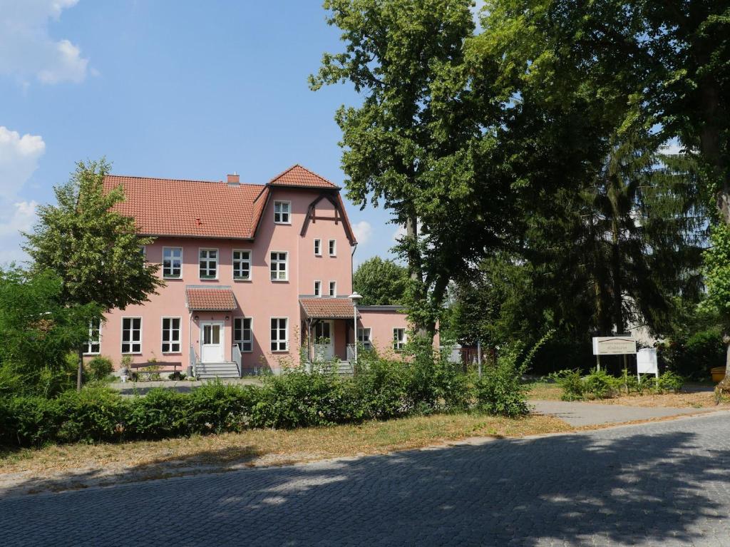 a large pink house on the side of a road at Touristisches Begegnungzentrum Melchow in Melchow