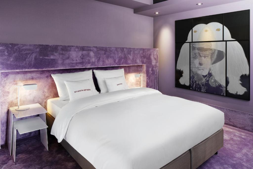 1 dormitorio con cama blanca y pared morada en 25hours Hotel The Goldman, en Frankfurt