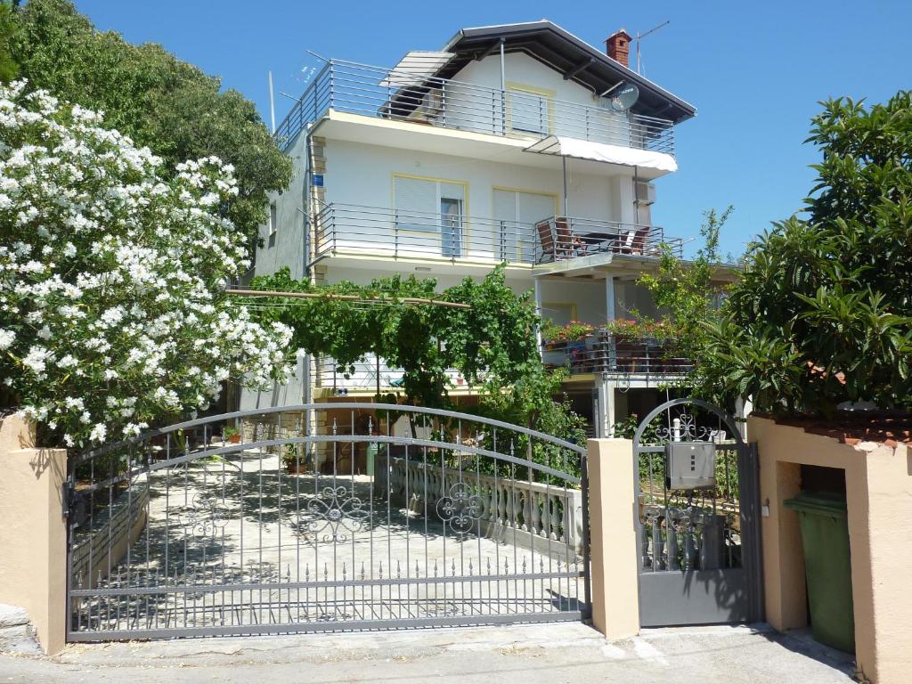 een wit huis met een poort en bomen bij Apartments Kresović in Vodice