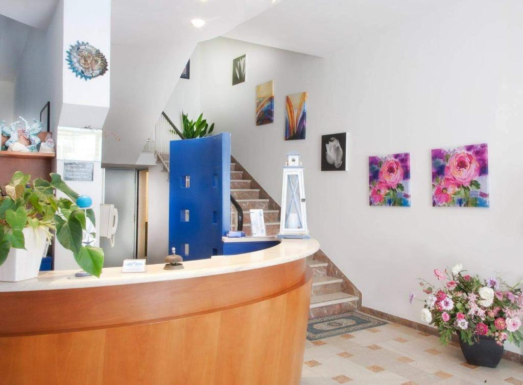 un salón con un mostrador azul y pinturas en la pared en Arix Hotel en Rímini