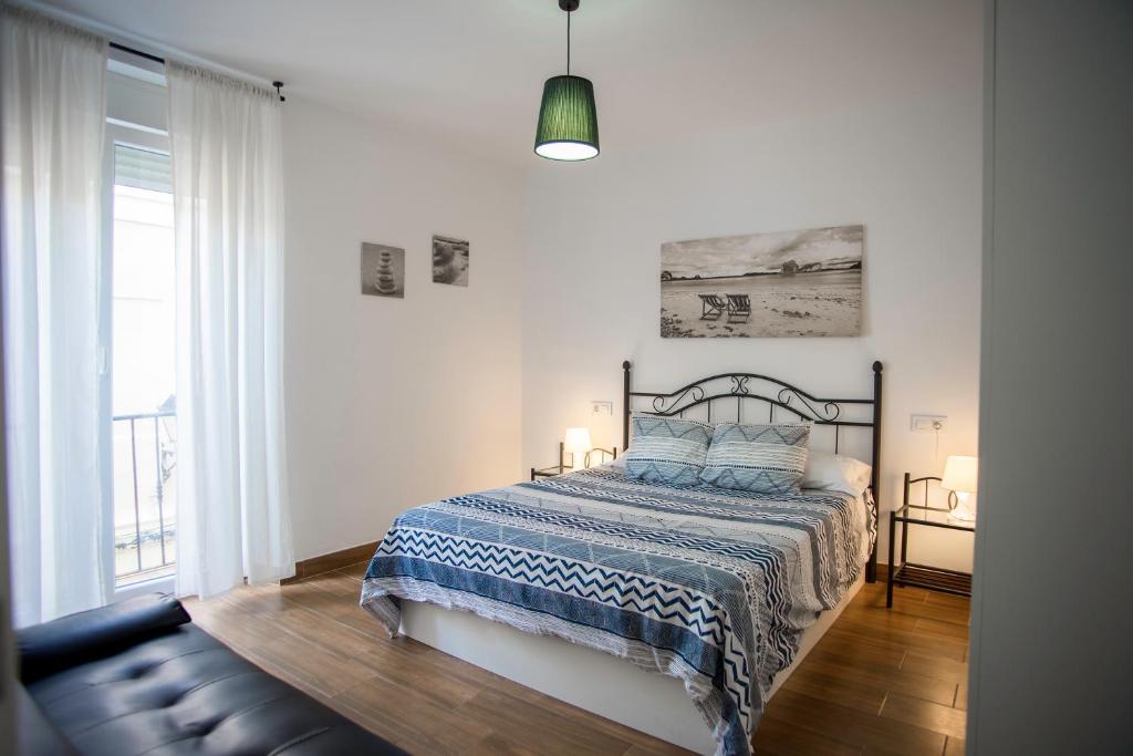 a bedroom with a bed with a blue and white blanket at La Luz del Falla Ha Apartment in Cádiz