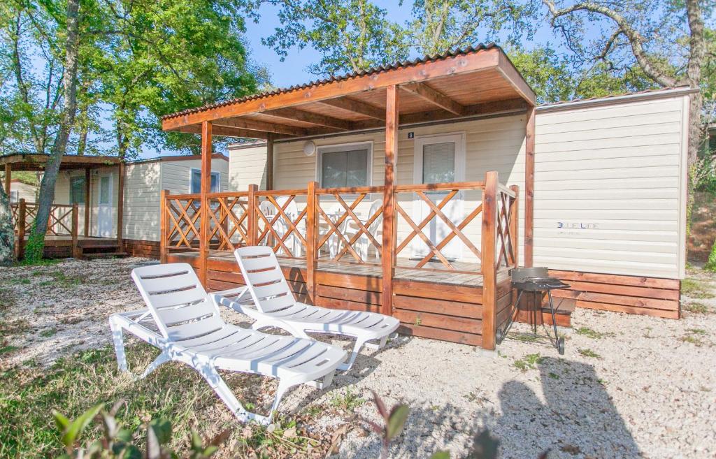 two chairs and a house with a cabin at CHERRY Premium BIANCA Mobile homes Zelena Laguna in Poreč