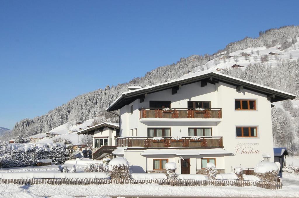 a large white building with a balcony in the snow at Appartements Charlotte in Westendorf