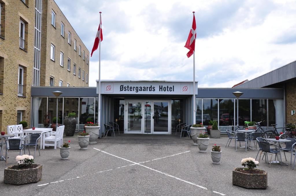 um restaurante com bandeiras em frente a um edifício em Østergaards Hotel em Herning