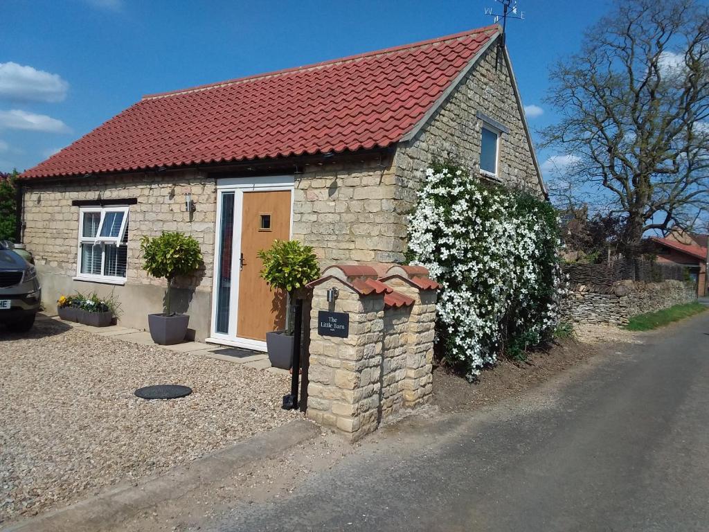 uma pequena casa de tijolos com telhado vermelho em The Little Barn em Carlby