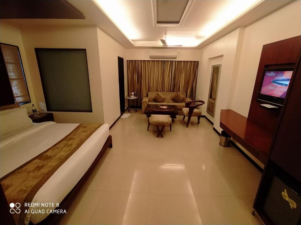 インドールにあるKyriad Hotel Indore by OTHPLのベッド、ソファ、テーブルが備わるホテルルームです。