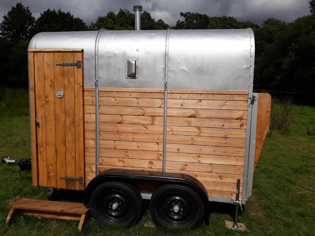 a small trailer sitting in the grass in a field at Beautiful Rural Yurt with Wood Fired hot tub 