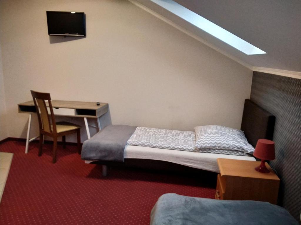 sypialnia z łóżkiem i biurkiem z telewizorem w obiekcie VENA Noclegi Restauracja Sala Bankietowa w mieście Malanów