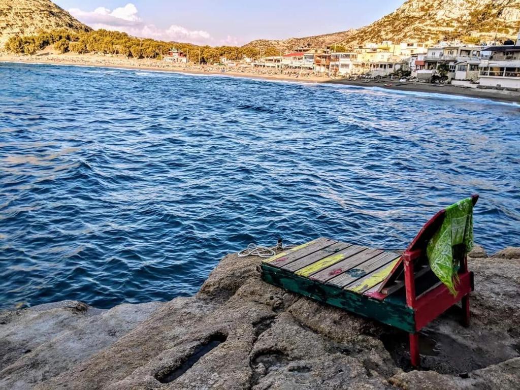 a bench sitting on a rock next to the water at Fantastic Matala 1 in Matala