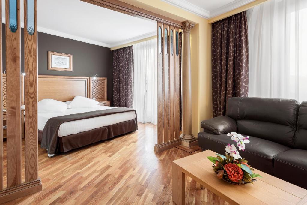 a hotel room with a bed and a couch at Exe Doña Carlota in Ciudad Real