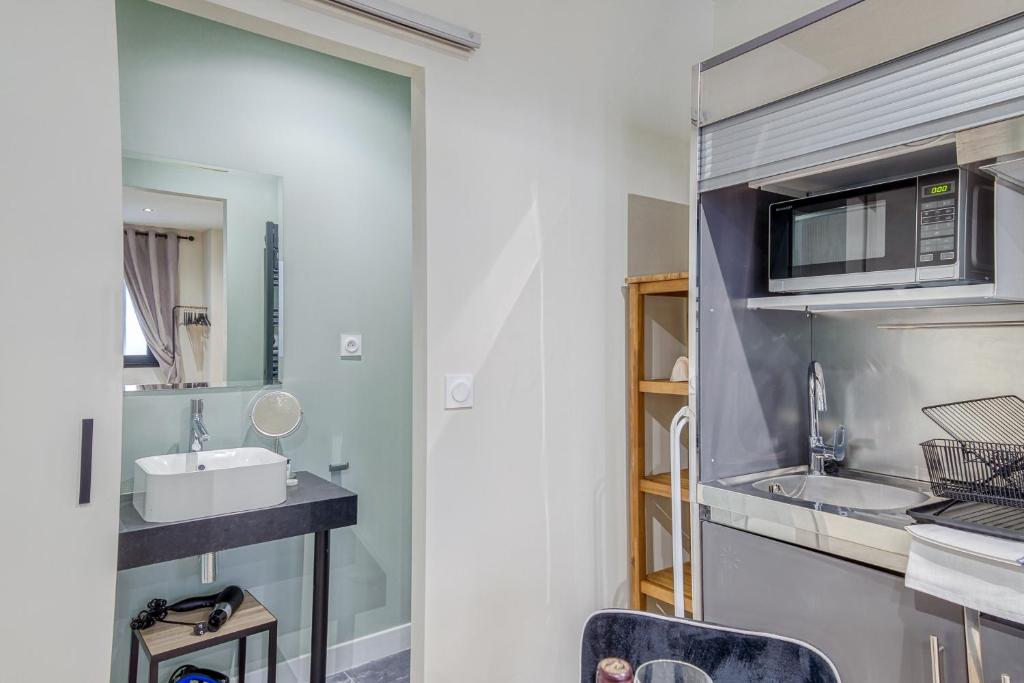 a bathroom with a sink and a microwave at Appartements Emile Fourcand in Bordeaux