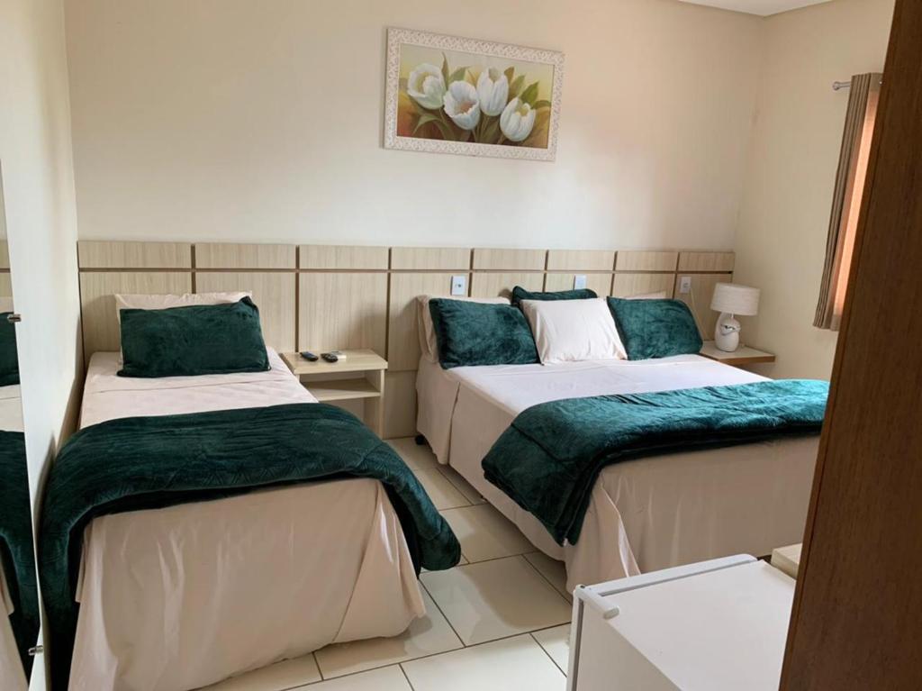 a bedroom with two beds with green and white sheets at Hotel Do Santo in Giruá