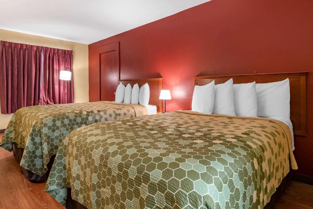 two beds in a hotel room with red walls at Econo Lodge Inn & Suites Maingate Central in Kissimmee