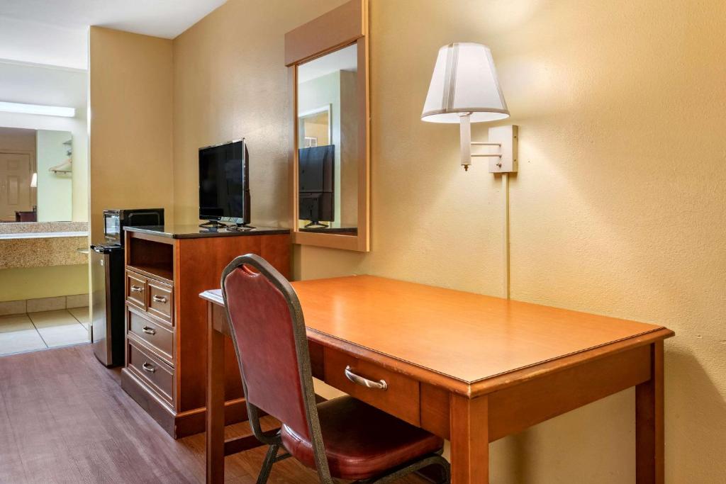 a desk in a hotel room with a chair and a lamp at Econo Lodge Inn & Suites Maingate Central in Kissimmee