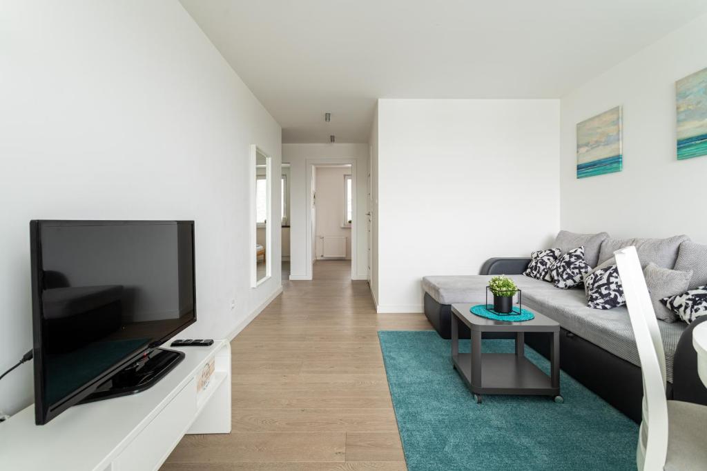 a living room with a couch and a flat screen tv at Victus Apartamenty, Apartament Malta in Sopot