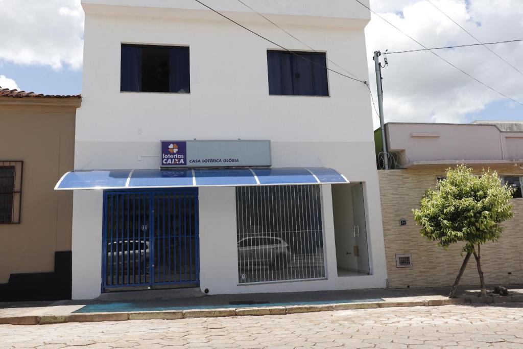 ein weißes Gebäude mit blauer Markise und einem Tor in der Unterkunft pouso praia vermelha in São João Batista do Glória