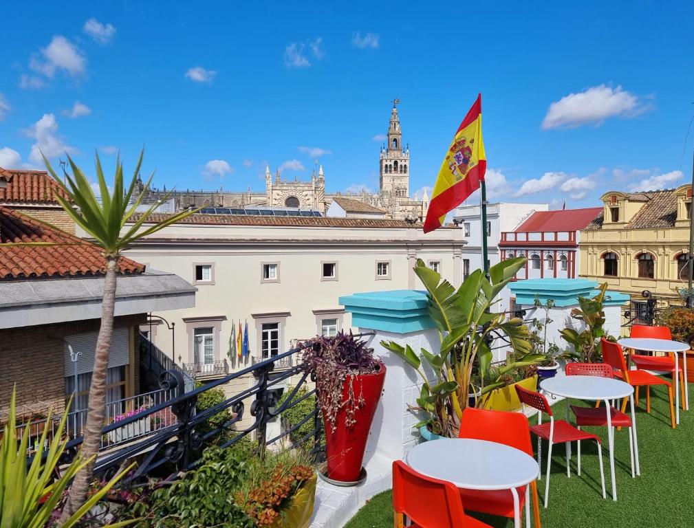 eine Terrasse mit Tischen und Stühlen auf dem Dach eines Gebäudes in der Unterkunft Sevilla Kitsch Hostel Art in Sevilla