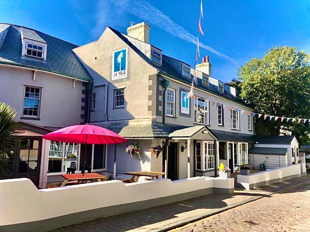 a large building with a red umbrella in front of it at La Ville Hotel in Alderney