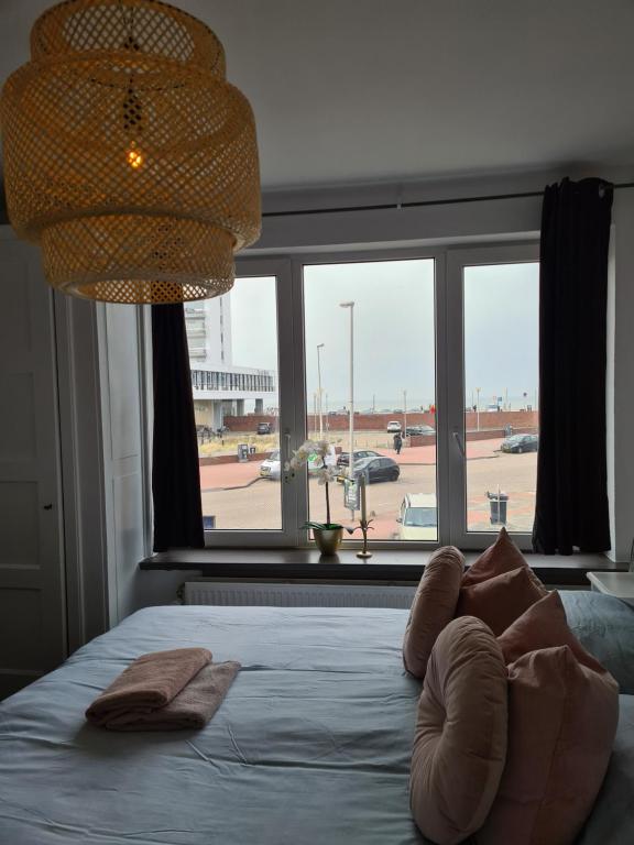 ein Schlafzimmer mit einem Bett mit Kissen und einem großen Fenster in der Unterkunft Evy's place in Zandvoort