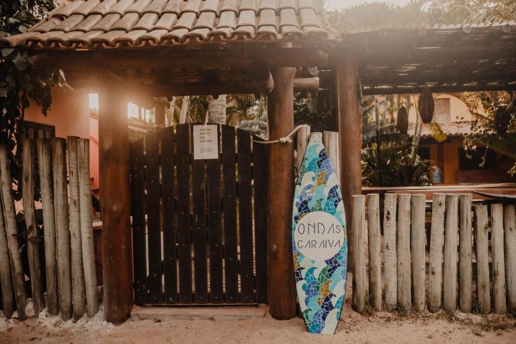 una valla de madera con una tabla de surf apoyada en ella en Onda´s Caraíva, en Caraíva