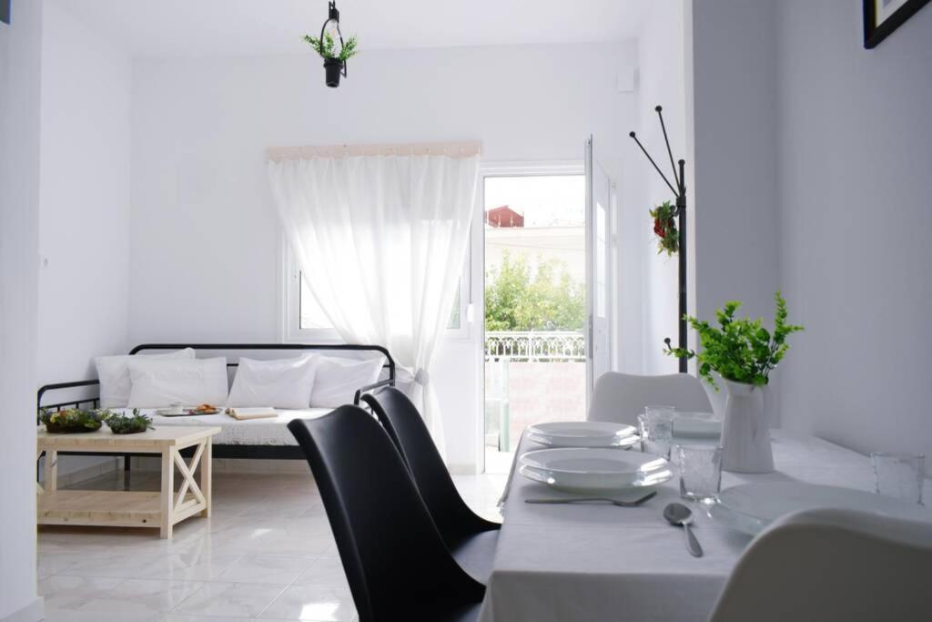 Habitación blanca con cama, mesa y sillas en Filia's Family Apartment, en Archangelos