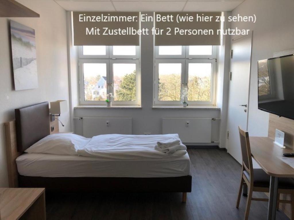 a bedroom with a bed and two windows at BusinessInn.de Aparthotel Bremerhaven in Bremerhaven