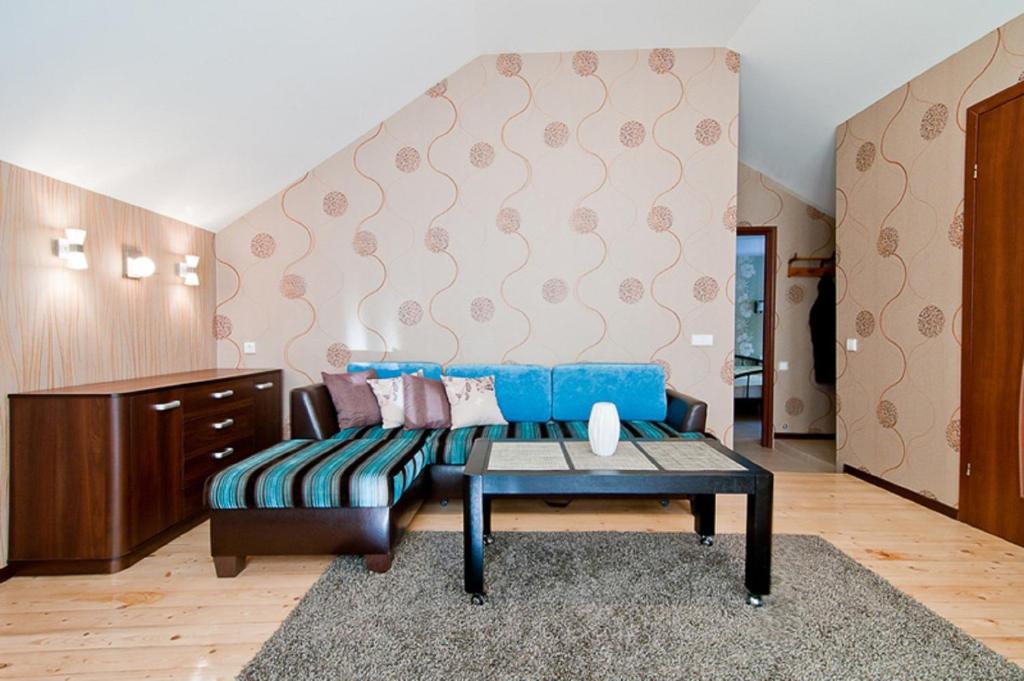 ein Wohnzimmer mit einem blauen Sofa und einem Tisch in der Unterkunft Abariaus Apartamentai in Druskininkai
